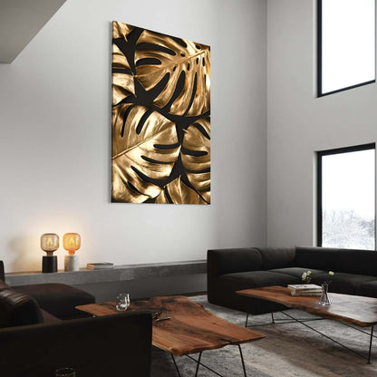 Goudkleurige wanddecoratie met monstera bladeren in moderne woonkamer.